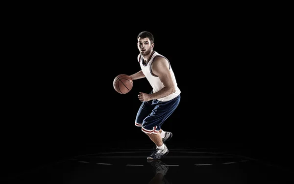 Professional basketball player holding ball on black background — Stock Photo, Image