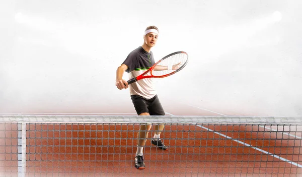 Молодой человек играет в теннис на корте — стоковое фото