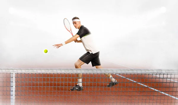 Молодой человек играет в теннис на корте — стоковое фото