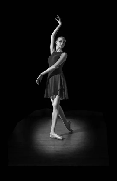 Junge und unglaublich schöne Ballerina posiert im dunklen Saal auf dem Parkett. — Stockfoto