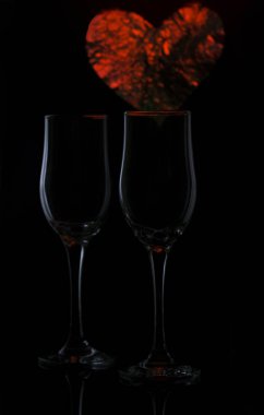 İki cam bardak kırmızı bir kalp ile siyah bir zemin üzerine