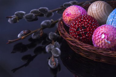 Söğüt dalları üzerinde karanlık bir arka plan ile sepet içinde çok renkli Paskalya yumurtaları