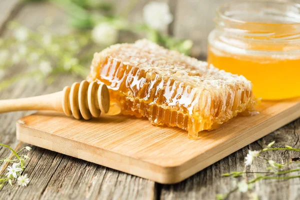 Panal sobre tabla de madera con cuchara de miel — Foto de Stock