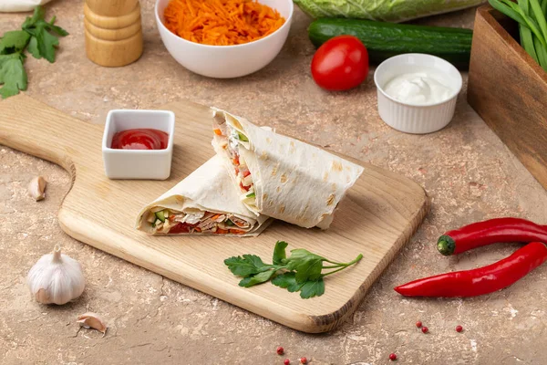Shawarma ahşap tahtada sos ve sebzelerle servis edilir.