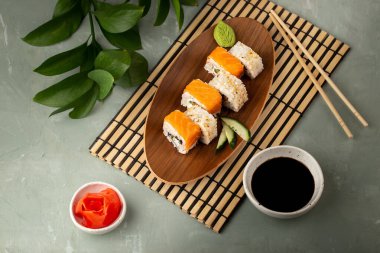 Ahşap tabakta farklı suşi ruloları, wasabi, zencefil ve soya sosu.