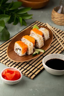 Ahşap tabakta farklı suşi ruloları, wasabi, zencefil ve soya sosu.