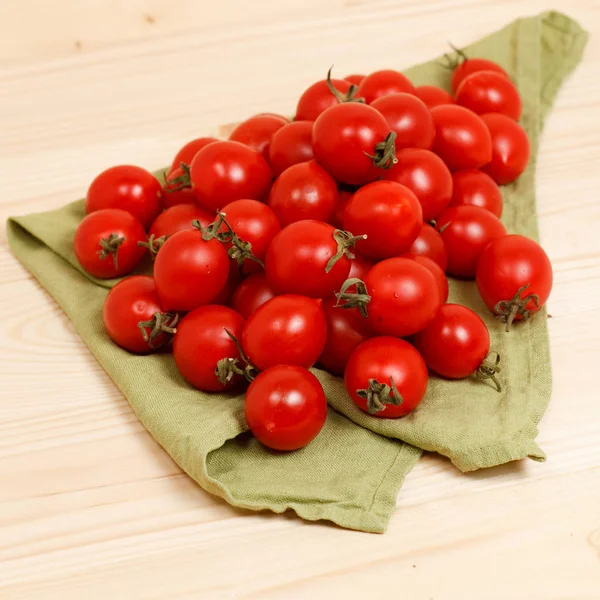 Tomates pequeños sobre tela verde fondo de madera — Foto de Stock