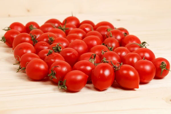 Small cherry tomatoes on light wooden background — Stock Photo, Image