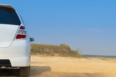 The back of a white car parked on a dirt road Outdoor environment and blue sky. clipart