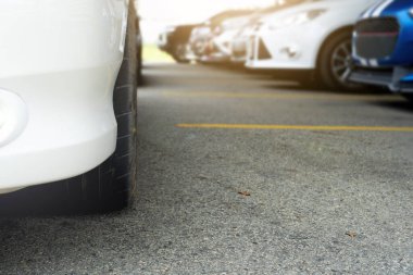 Otoparkta asfalt yolda sarı çizgili arabalar var..