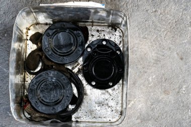 Arabanın içinde bir parça. Yağla kaplanmış, temizlik ya da bakım için konteynıra konmuş.. 