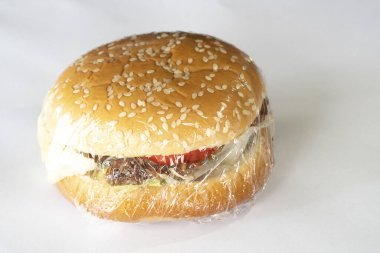 Beyaz arka planda ev yapımı kızarmış domuz hamburgeri. Plastik folyo kule paketinde.