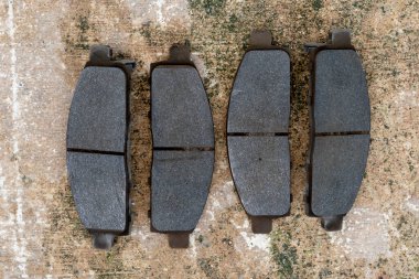 Beton arka planda dört kullanılmış araba fren pedi. Tamirat işleri için.