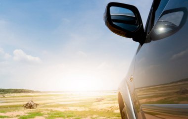 Lüks araba grisi renginin yanı sıra geniş alanda turizme gidiyor. Arabadaki güneş ışığı ve yansımalarla..