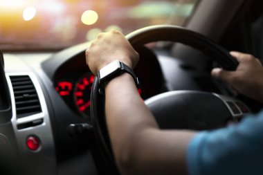 Erkeğin seçici odak eli. Arabanın direksiyonunu tut. Arabanın camının dışında sıcak renkli ve bokeh bir görüntü var..