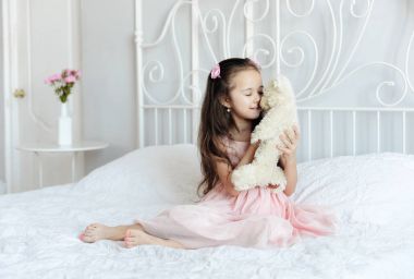 sevimli kız yatakta oyuncak ayı ile sabah oynarken