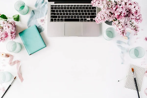 Workspace with paintbrush, laptop, lilac flowers bouquet
