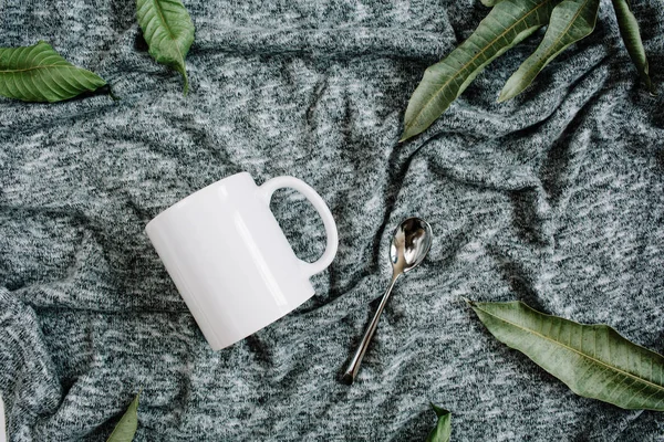 Blank template of white mug, spoon and green leaves — Stock Photo, Image