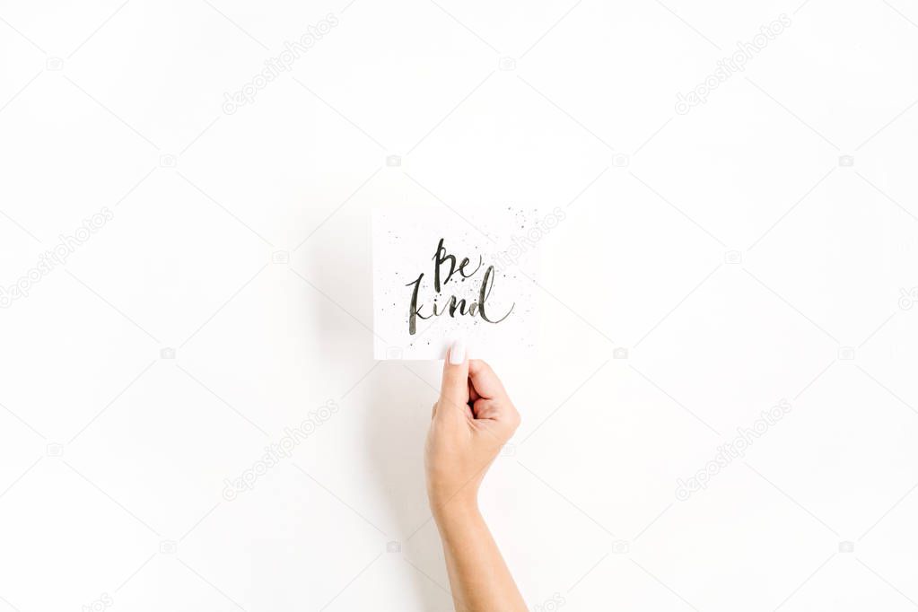 omposition with girl's hand holding card with quote Be Kind