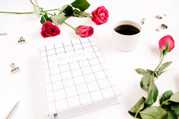 Red roses flowers, coffee cup, notebook and clips