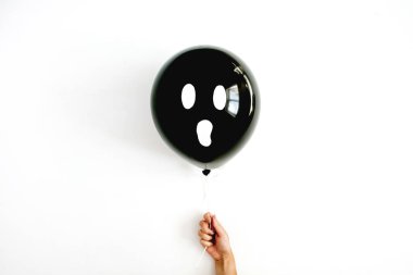 Kızın elinde korkunç yüzü olan bir siyah balon