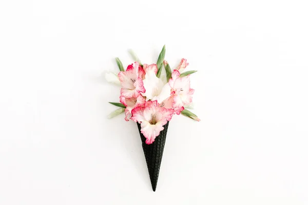 Schwarze Waffelkegel mit trockenen rosa Gladiolenblüten — Stockfoto