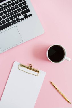 En az kadınlar Anasayfa office masaüstü laptop, Pano, kalem, kahve kupa üzerinde pembe bir arka plan ile. Düz yatıyordu, en iyi görünümü çalışma alanı kavramı.