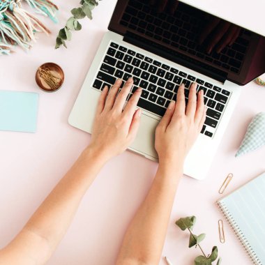 Düz yatıyordu ev ofis büro. Laptop, okaliptüs şube, pembe bir arka plan üzerinde aksesuarları ile kadın çalışma alanı. Üstten Görünüm kadınsı arka plan. Yaşam tarzı blog kahraman.
