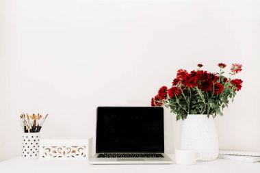 Ofis büro dizüstü bilgisayar ve güzel kırmızı çiçekler buket