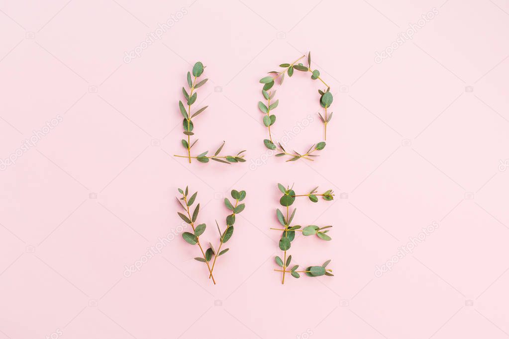 Word Love made of eucalyptus branches on pink background. Valentine's Day concept. Flat lay, top view.