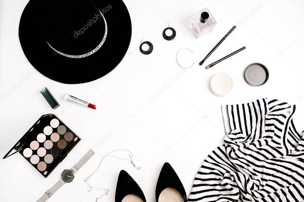Woman fashion flatlay. Frame of modern clothes, accessories and cosmetics. T-shirt, hat, shoes, palette, lipstick, watches, powder on white background. Flat lay, top view.