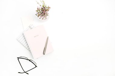 Kadın modern en az ev ofis Masası defter, gözlük, kalem ve kır çiçekleri buketi beyaz arka plan üzerinde bulunmaktadır. Düz yatıyordu, en iyi görünümü blog kompozisyon.
