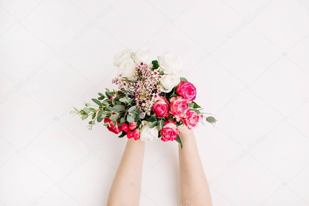 Female hands hold bridal flowers bouquet with roses, eucalyptus branch, wildflowers. Flat lay, top view wedding background.