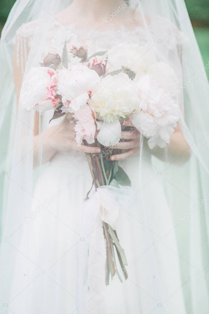 Bride holding beautiful wedding bouquet of peony flowers. Bridal fashion concept.