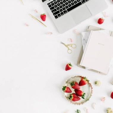 Laptop, defter, ruj, beyaz zemin üzerine taze çiğ çilek ile kadın çalışma alanı. Düz yatıyordu, en iyi görünümü.