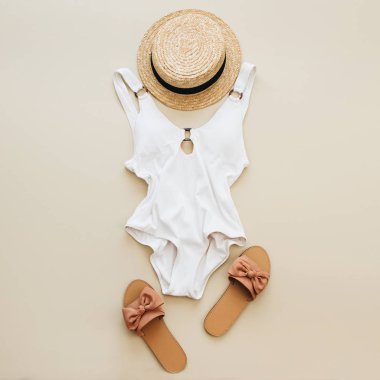 Düz yatıyordu yaz moda kompozisyon. Kadın mayo, saman ve terlik pastel bej renkli arka plan üzerinde. Düz yatıyordu, en iyi görünüm çok az beach kavramı.