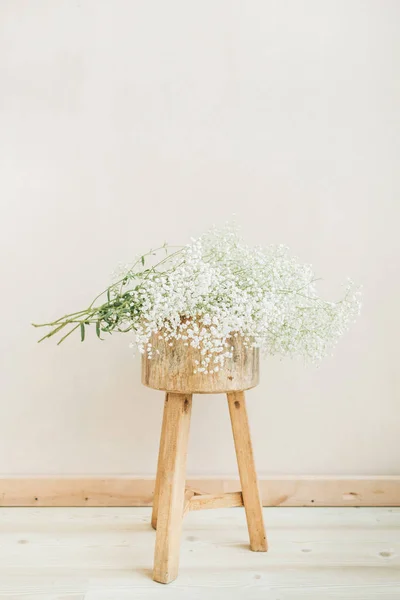 白の淡いパステル ベージュ色の背景に木製のスツールにカスミソウの花束 最低限の生活の概念 — ストック写真