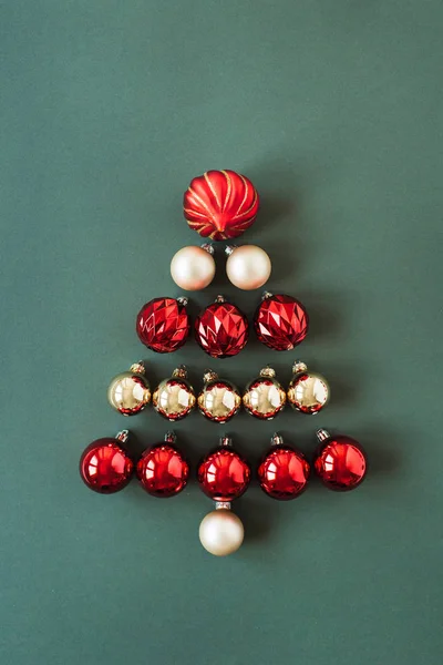 緑の背景に赤と金のクリスマスのボール ボールで作られたクリスマスツリーのシンボル フラットレイ トップビュー新年 クリスマスの休日の組成 — ストック写真