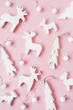 Noel / Yeni Yıl bayramı kompozisyonu. Noel mücevherleri, oyuncak geyikler, pembe arka planda köknar ağacı. Düz, üst görünüm şenlik deseni.