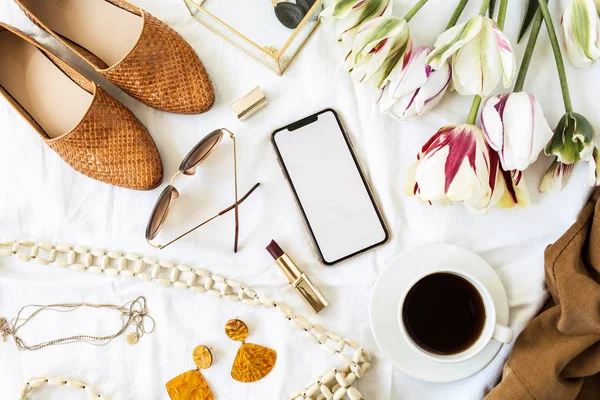 ファッション 美容ブロガーホームオフィスデスク 空の画面スマートフォン チューリップの花の花束 服やアクセサリー白いリネン フラットレイアウト トップビューライフスタイル組成 — ストック写真