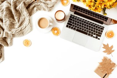 Ofis masası çalışma alanı dizüstü bilgisayarla süslenmiş sarı papatya çiçekleri, kahve fincanı, portakal dilimleri, ekose. Düz konum, üst görünüm serbest iş konsepti sosyal medya, dergi.