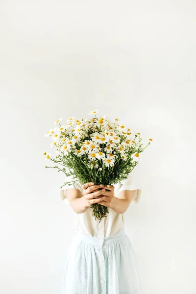若いです可愛いです女性でベージュブラウスホールドで手の花束の白いカモミールデイジー花上の白い背景 — ストック写真