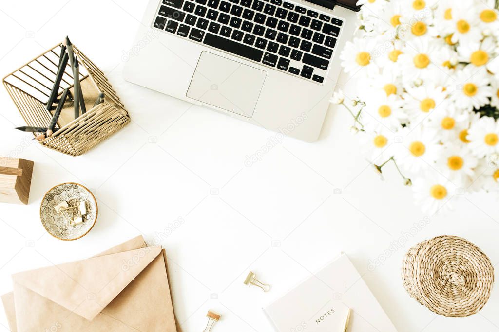 Home office desk workspace with laptop, chamomile daisy flowers bouquet and notebook on white background. Flat lay, top view minimal freelancer work concept with copy space mockup.