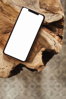 Saf ahşap tabure ve halıya boş fotokopi alanı modeliyle boş ekran cep telefonu. Düz konum, sosyal medya, web sitesi, dergi için üst görünüm şablonu.