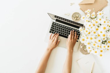 Kadın elleri kompozisyonda çalışır. Bilgisayarlı ofis masası çalışma alanı, papatya çiçeği buketi ve beyaz arka planda not defteri. Düz konum, üst görünüm freelancer konsepti kopyalama alanı modeliName.