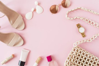 Çerçeve çerçevesi, pembe arka planda kadın aksesuarları olan yaz moda kompozisyonundan yapılmış. Çanta, parfüm, güneş gözlüğü, ayakkabı, küpe, ruj, saat. Düz konum, üst görünüm boş kopyalama alanı modeli.