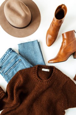 Beyaz arka planda kadın moda kolajı, modern kıyafetler ve aksesuarlar vardı. Kahverengi yün kazak, ayakkabılar, şapka, kot pantolon. Yaşam tarzı, blog için güzellik konsepti, sosyal medya, dergi.