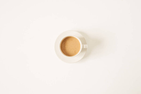 Cup of coffee with milk on white table. Minimal morning breakfast concept. Flat lay, top view.