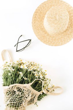 Hasır şapkalı asgari moda konsepti, papatya çiçekli ip torbası, bardaklar. Düz yatış, üst görünüm.