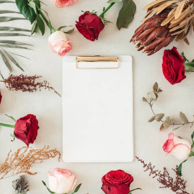 Pembe, kırmızı gül çiçekleri, protea, tropikal palmiye yaprağı, bej arka planda okaliptüs çerçevesinde metin için boş kopya alanı bulunan düz bir pano. Üst görünüm çiçek modeli.